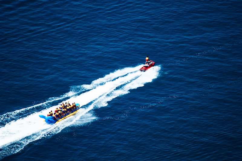 Group on a banana boat towed by a a jetsky in the middle of the ocean