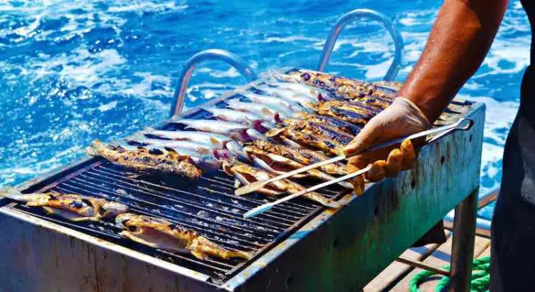 Man cooking freshly caught fish on his boat grill