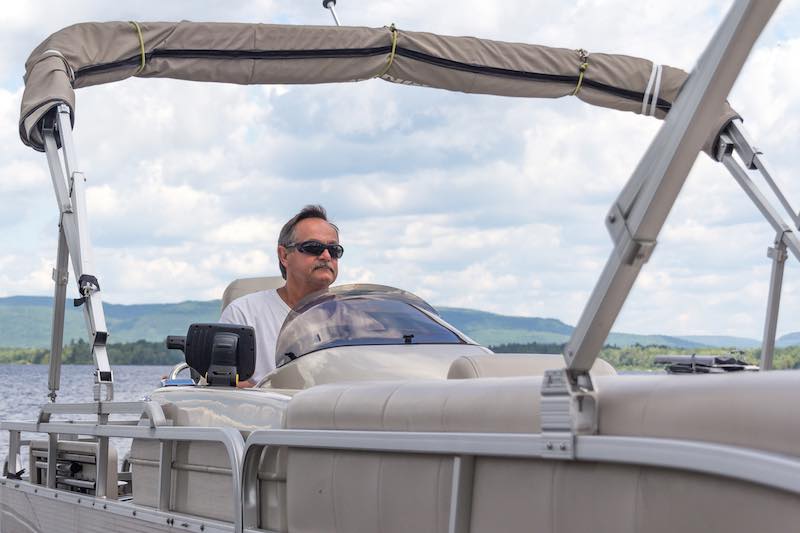 Man Driving a Pontoon Boat on a Lake