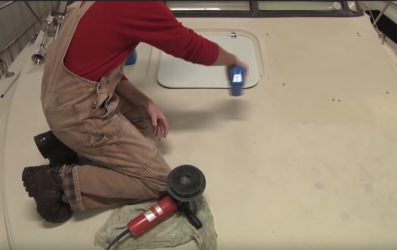 Man kneeled cleaning a boat deck