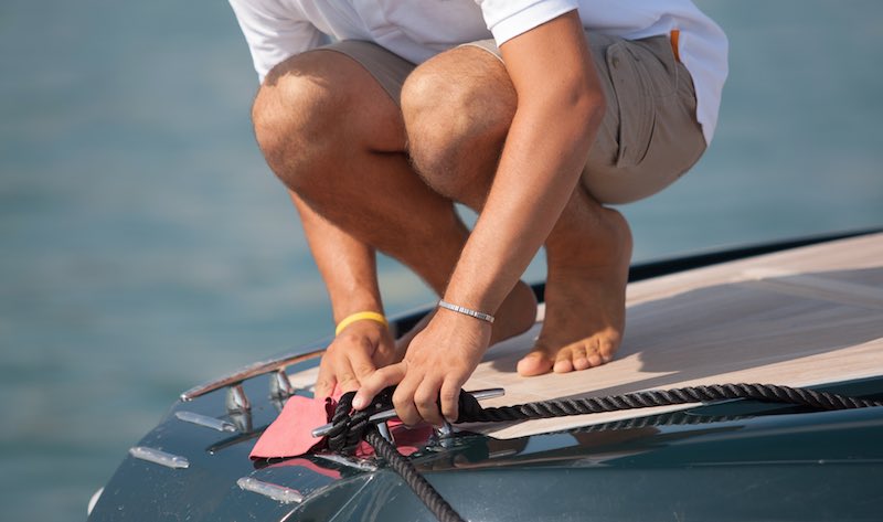 Barefoot sailor cleaning boat deck with pink wet rag. Personal Hygiene