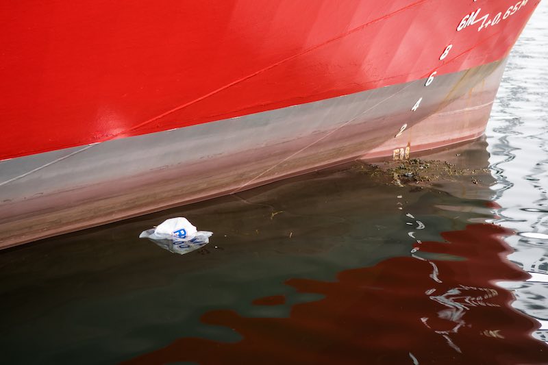 Plastic bag floating by a red boat in the water