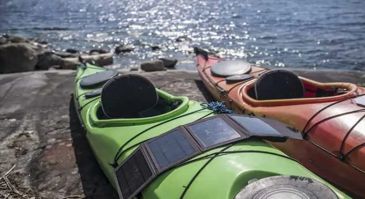 Two kayaks and a portable solar panel on a lake shore