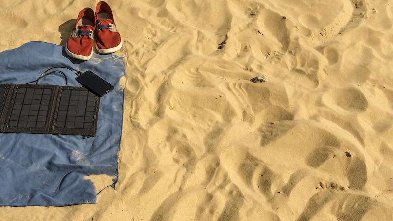 Portable foldable solar panel with power bank on a blanket on a beach