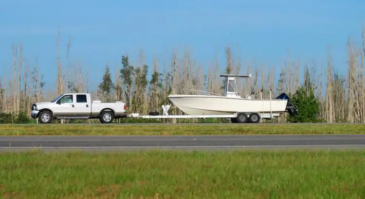 White truck pulling a boat trailer with a boat on it