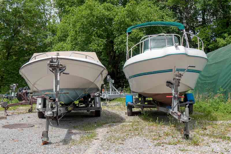Two white boats on different boat trailers