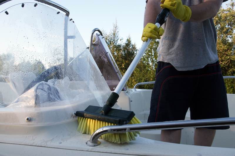 Man cleaning boat interior with broom