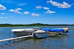 pontoon boat lift by a dock on a sunny day