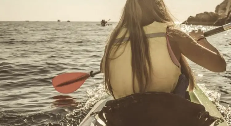 Woman paddling while sitting on a paddleboard seat